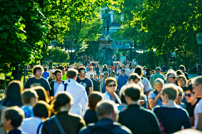 Ihmisiä kesäisessä Esplanadinpuistossa. Taustalla Runebergin patsas.